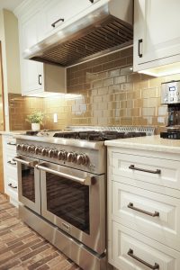 Beautiful newly renovated kitchen with brick flooring and large commercial grade range and range hood. Glass backsplash.