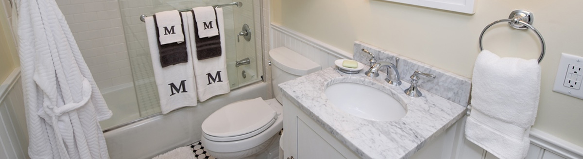 Small bathroom remodel in Toledo, Ohio. Shower with glass walls, small toilet and 1 sink. The letter M is monogramed on the towels.