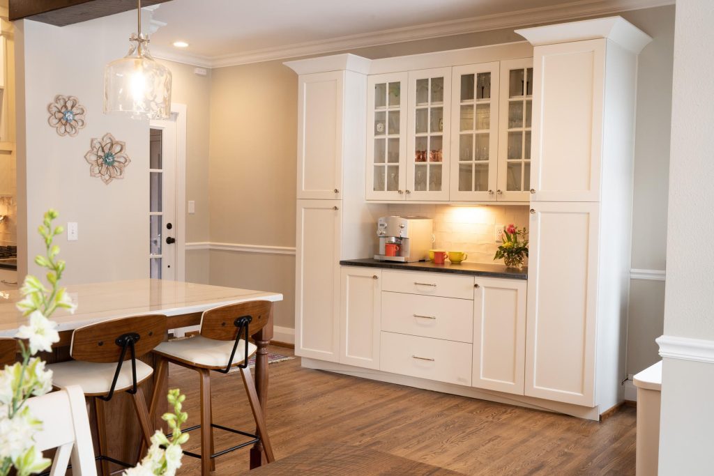Built in storage solution with glass-front cabinets and a countertop for small appliances in a white kitchen.