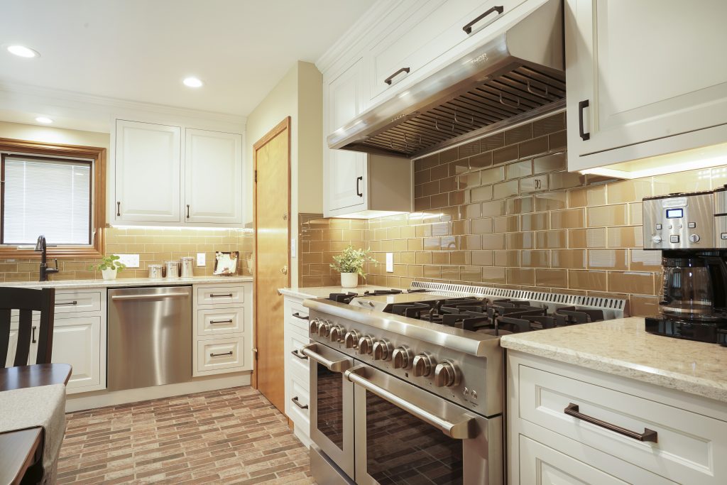 Modern kitchen remodel with large gas range and new glass tile backsplash.