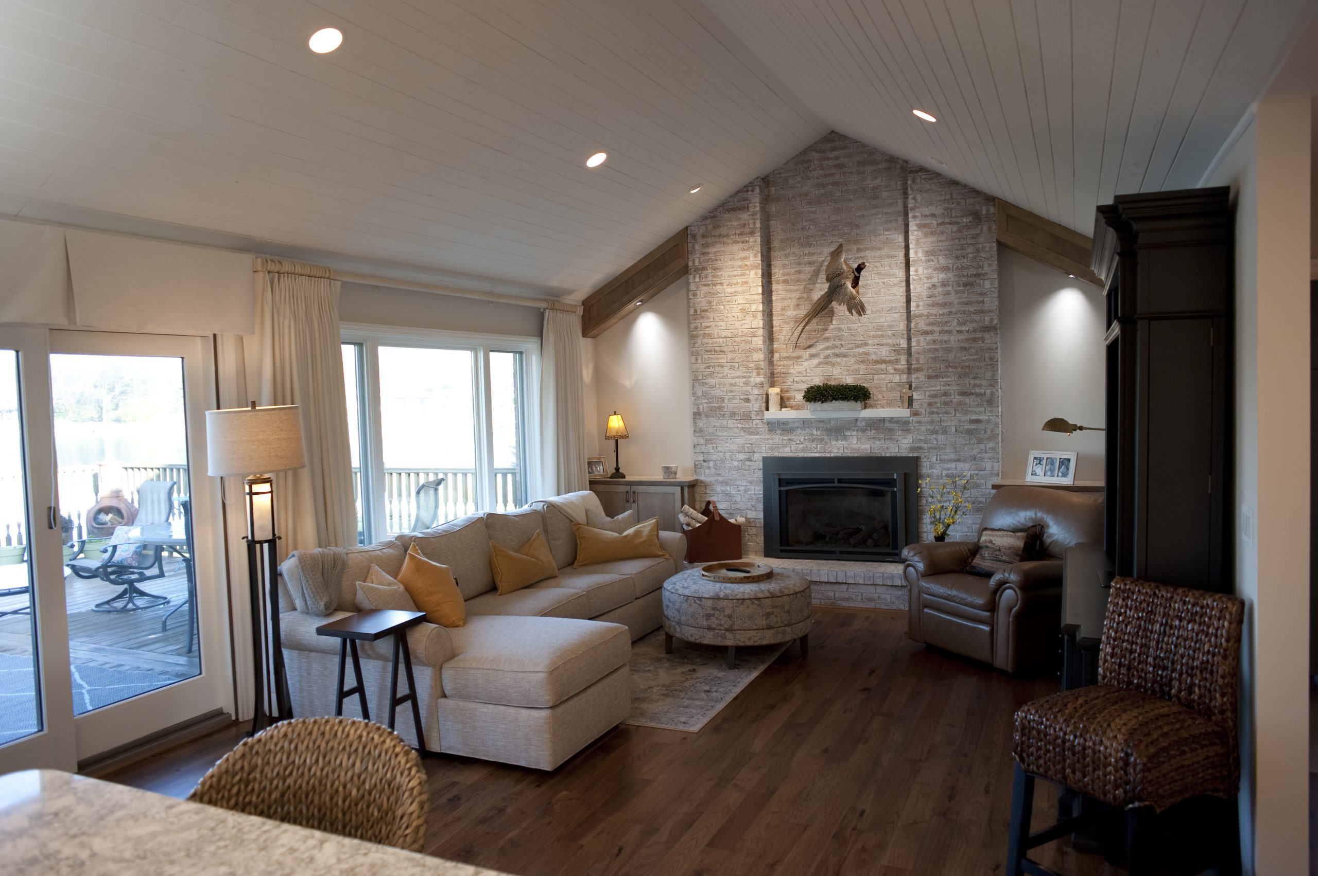 Renovated living room with soft neutral colors, vaulted ceilings, and a brick fireplace. 
