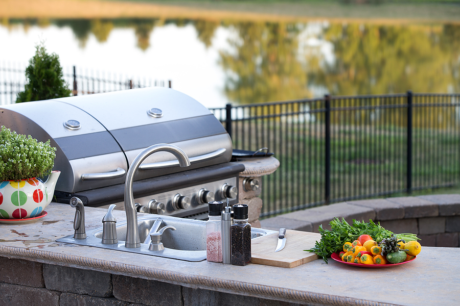 Closeup of a grill, countertop and sink in an outdoor kitchen.