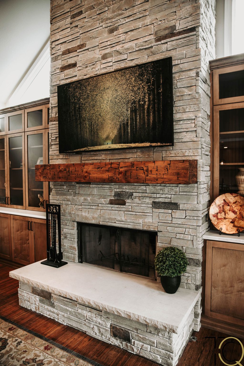 Custom stone fireplace remodel with rustic wood mantel and built-in cabinetry for a warm, modern living room design.