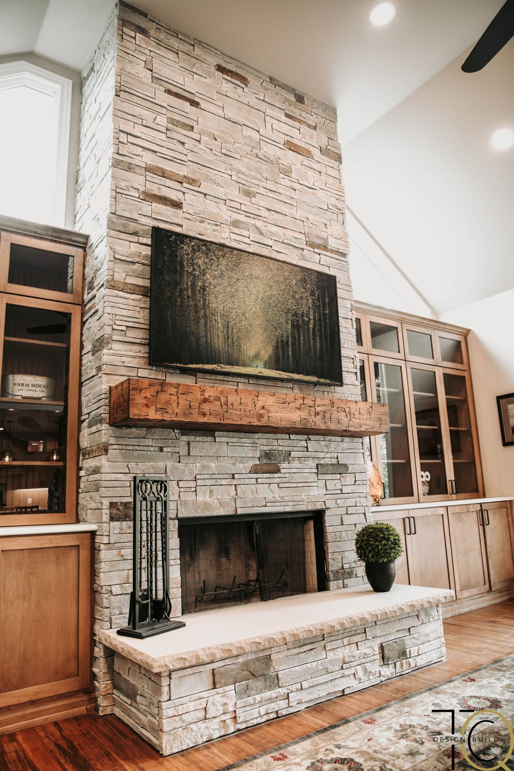 Custom stone fireplace remodel with rustic wood mantel and built-in cabinetry for a warm, modern living room design.