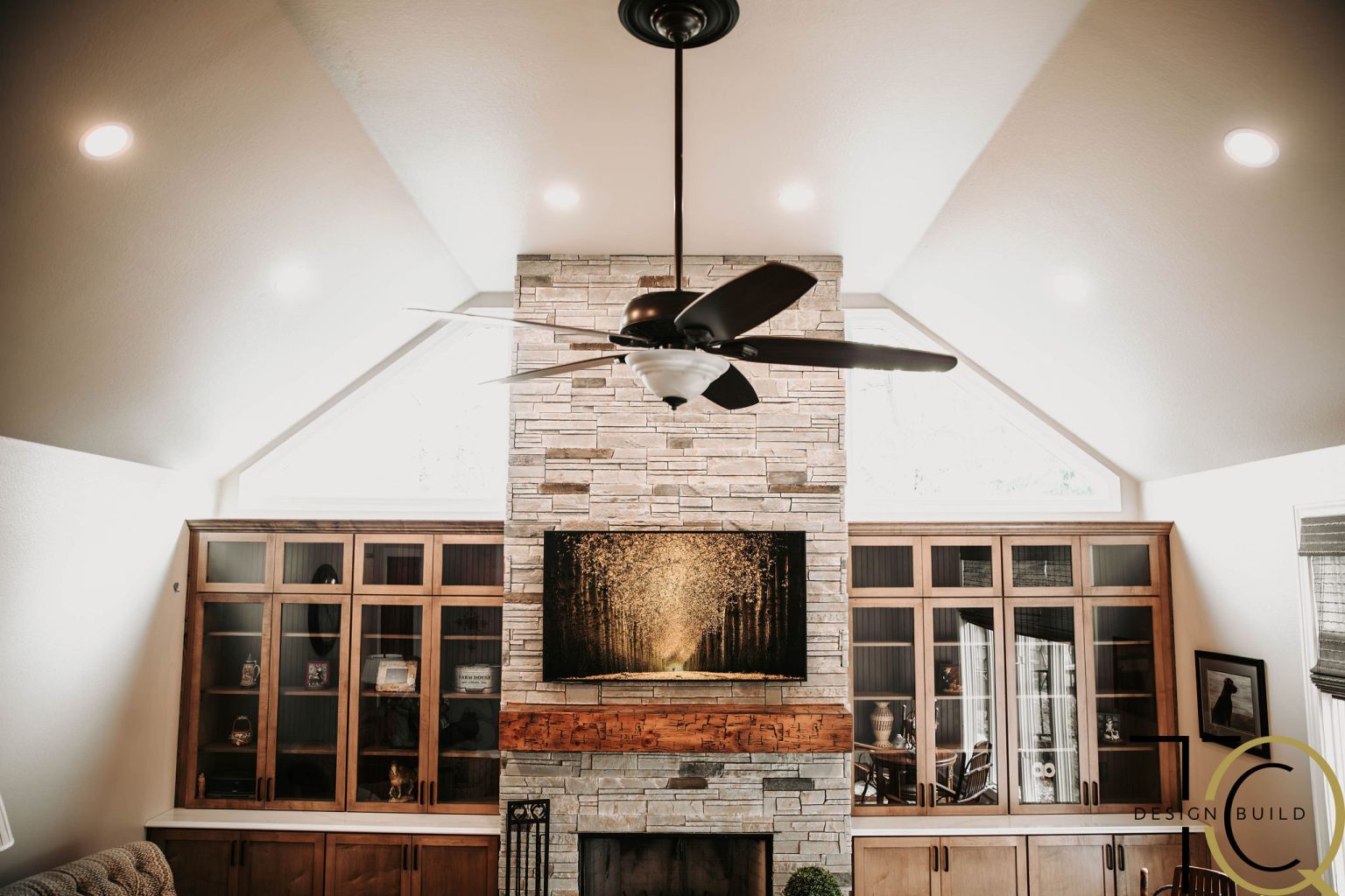 Monclova living room remodel with vaulted ceiling, modern ceiling fan, stone fireplace, and custom built-in cabinetry.