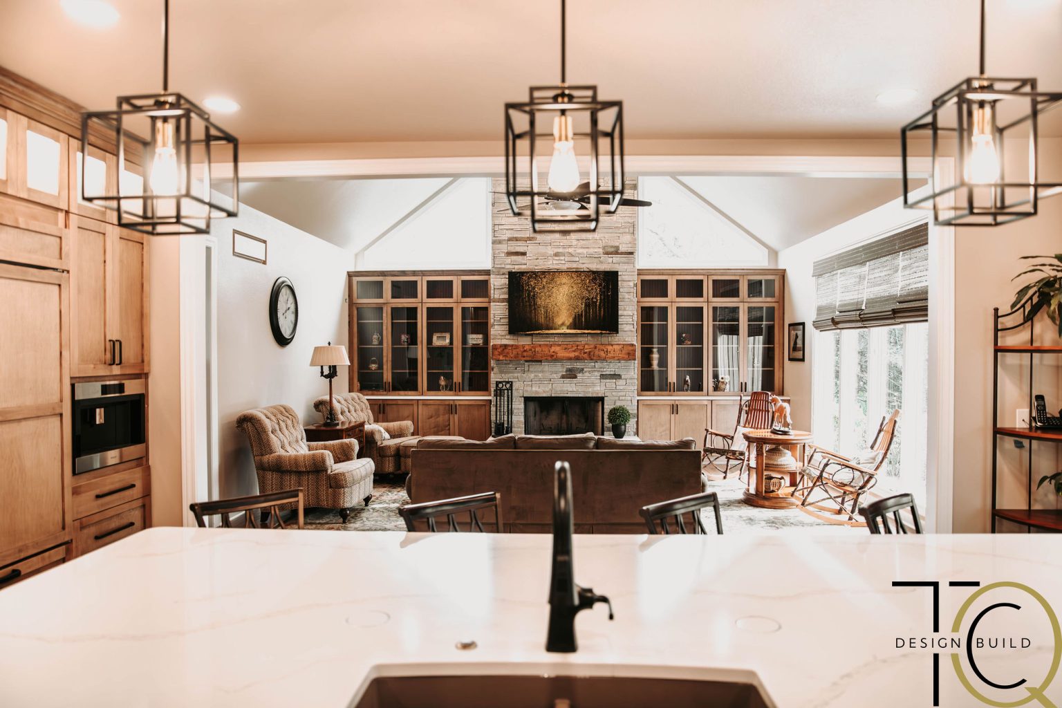 Great room remodel featuring modern pendant lighting over open concept living space with stone fireplace and built-in cabinetry.