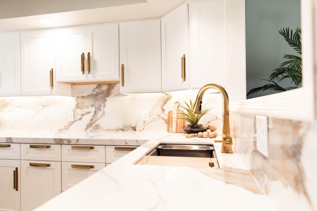 Closeup of a kitchen remodel, featuring gold fixtures and marble countertops. 